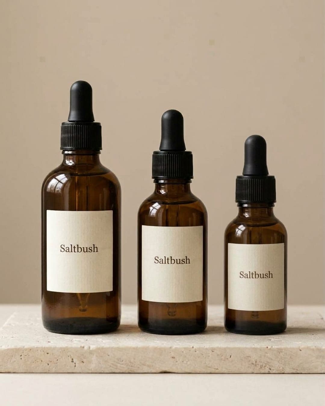 Three amber Saltbush dropper bottles in a row on a stone plinth in soft daylight