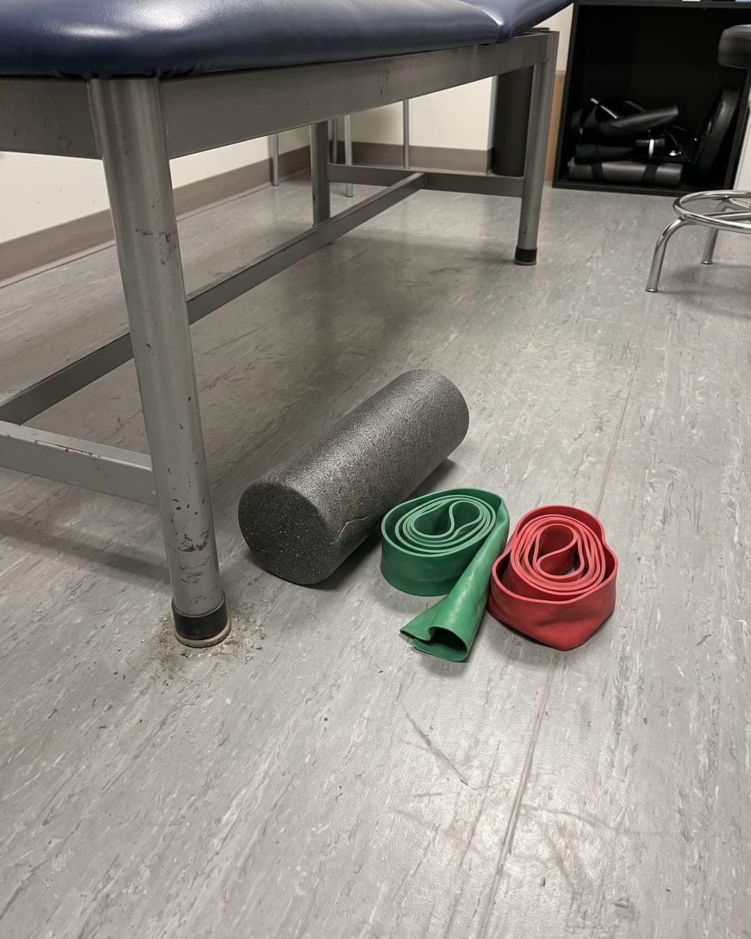 Phone photo of resistance bands and a foam roller on a clinic floor